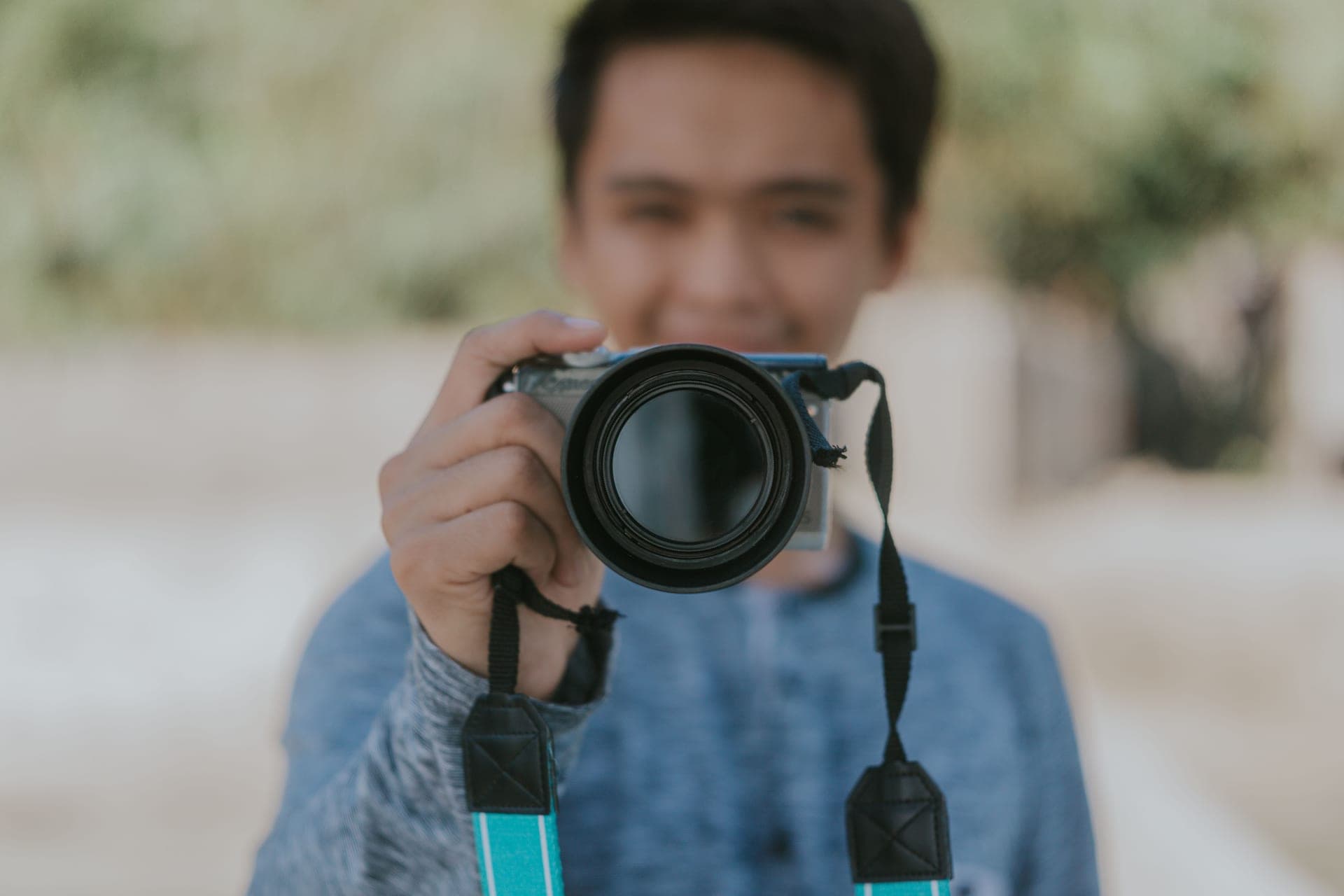 A creator holding a mirrorless camera in warm golden-hour light with a softly blurred background